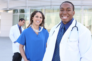 Female and Male Medical Professionals smiling outside of a Hospital building