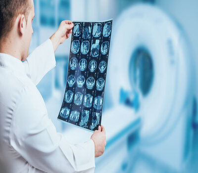 Male Physician going over a brain x-ray in front of an MRI Room.
